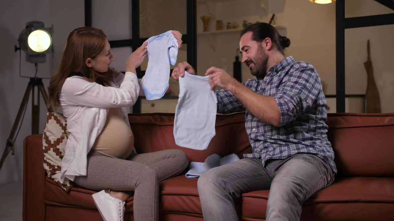 Pregnant woman looking at baby clothes with her husband