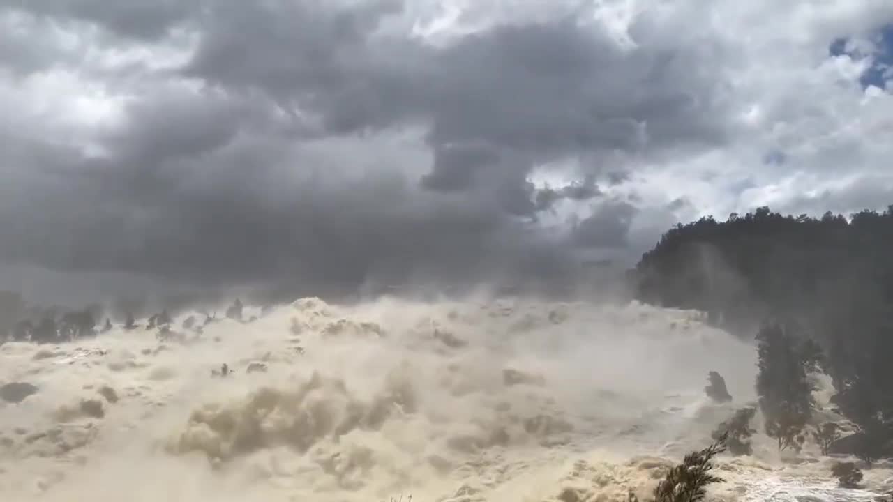 Moment raging river crashes over a dam in New South Wales