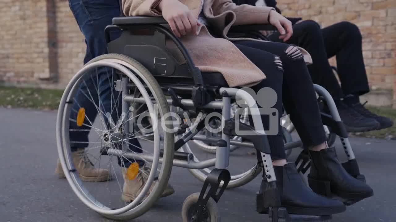 Camera Focuses On Wheels Of A Wheelchair Spinning On A Walk In The Street