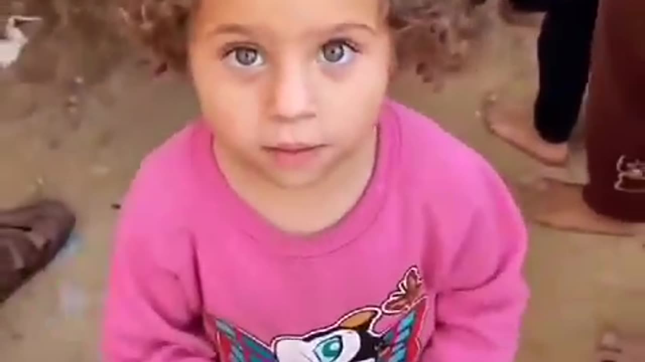 A little Palestinian girl stands barefoot in line at a food distribution center