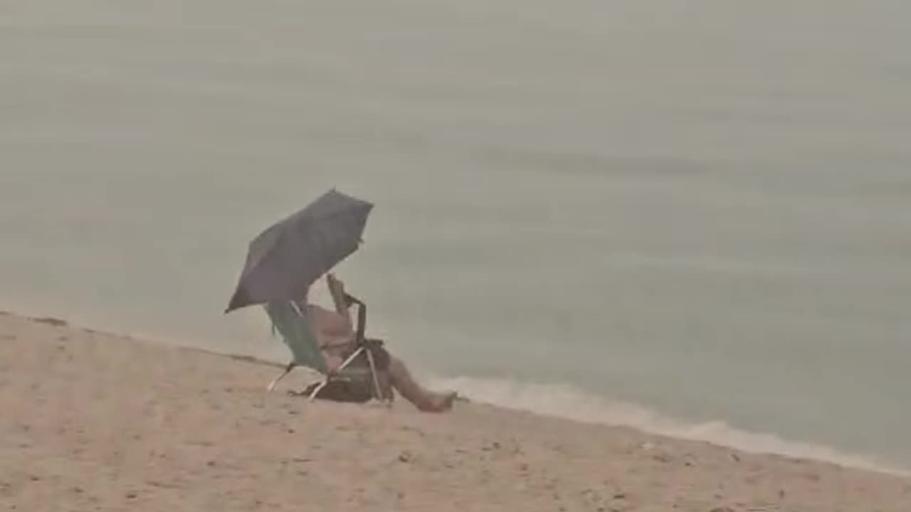 Man Doesn't Let Rain Ruin His Beach Day