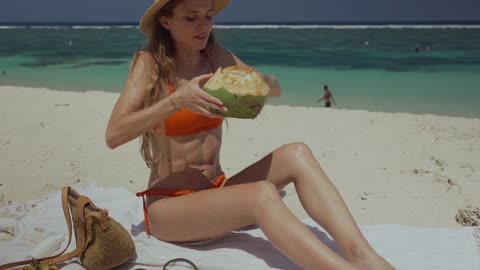 Cute lady enjoying coconut milk by the sea