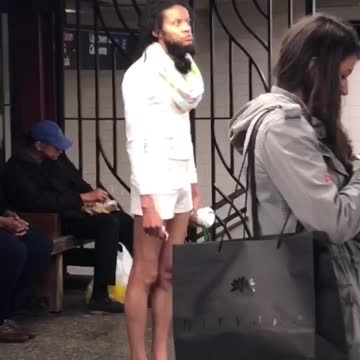 A man in all white outfit looks around in a subway