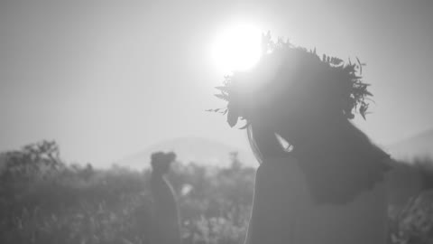 Women wearing a wreath of flowers walking and dancing in the field