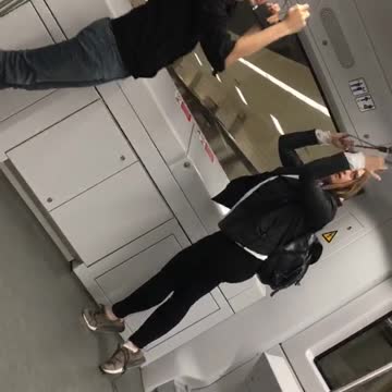 Couple hang from ropes on back of subway