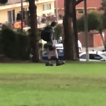 Guy with backpack on rollerblades walks on grass