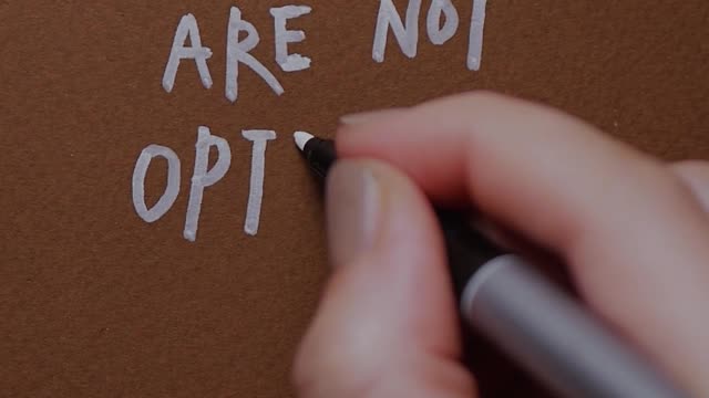 A Person Writing a Phrase on Brown Paper