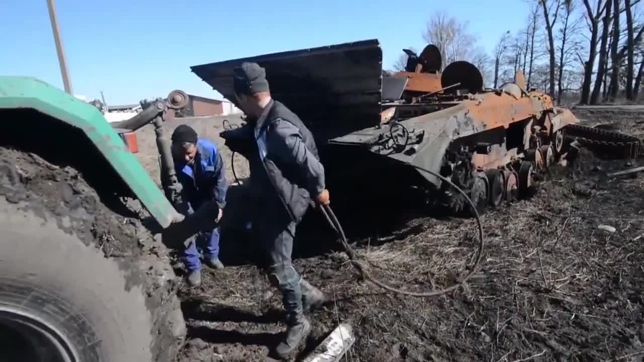 Efforts to remove the wreckage of a Russian BMP by an Ukrainian tractor.