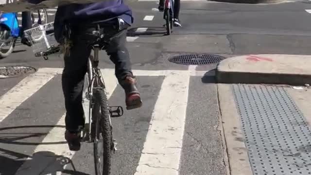 Man on bike rides with large ladder