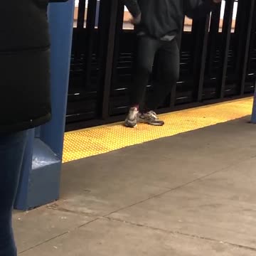 Man dances at the edge of subway station platform to guitar song