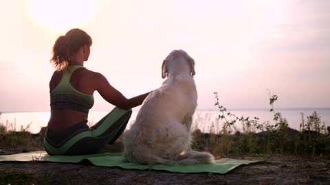 Young woman meditating with her dog aside near sea