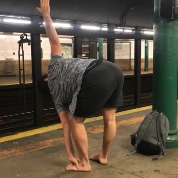 Barefoot man does yoga on subway platform