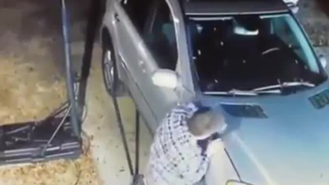 Man held his hand in the hood of the car.