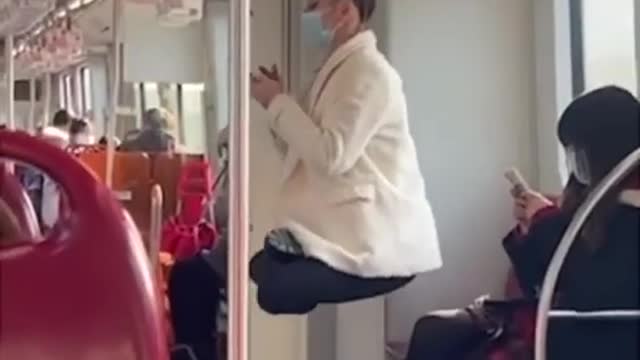 Woman swings off a subway handrail by her hair