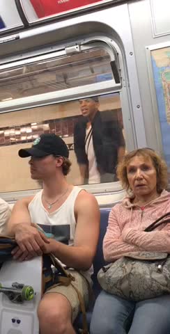 Guy white shirt dancing in front of subway window reflection