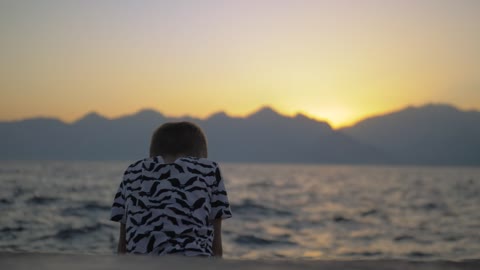 Lonely boy sitting on the seashore