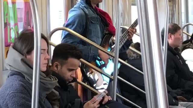 Man sings and plays bass guitar on subway train