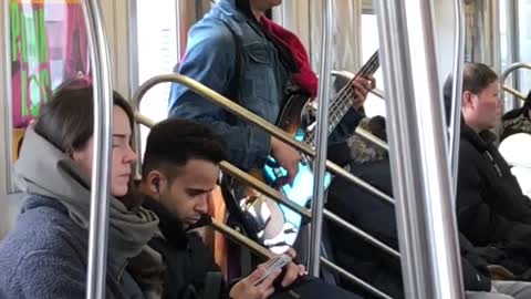 Man sings and plays bass guitar on subway train 