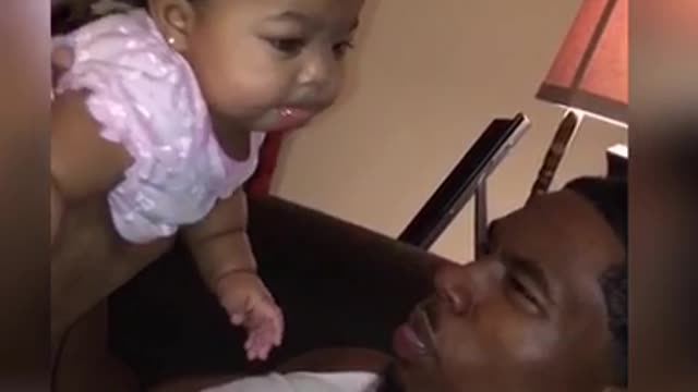 Cute baby girl loves blowing spit bubbles with Dad