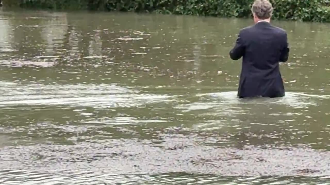 Fully Suited Man Wades Through Floodwater