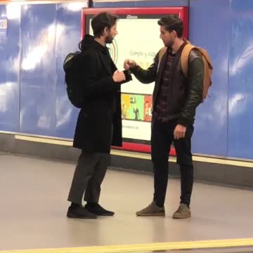 Two men play fight with their arms at subway station