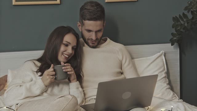 A Couple In Bed Watching Something From A Laptop