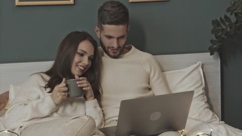 A Couple In Bed Watching Something From A Laptop