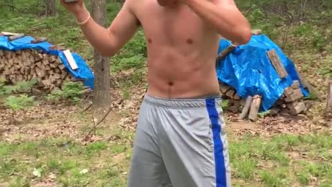 Shirtless guy in grey shorts tries to crack open a beer over his head