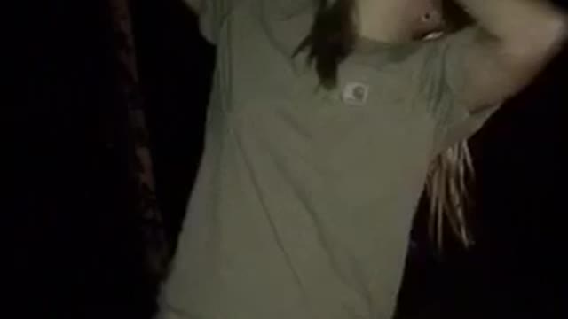 Blonde girl shotguns beer and then catches a football near a fire