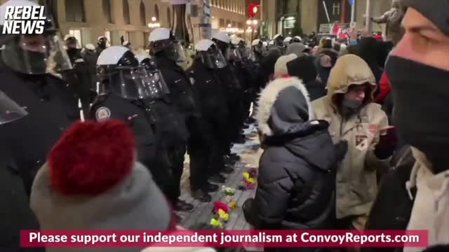 PROTESTORS PUT FLOWERS ON THE GROUND IN FRONT OF RIOT POLICE