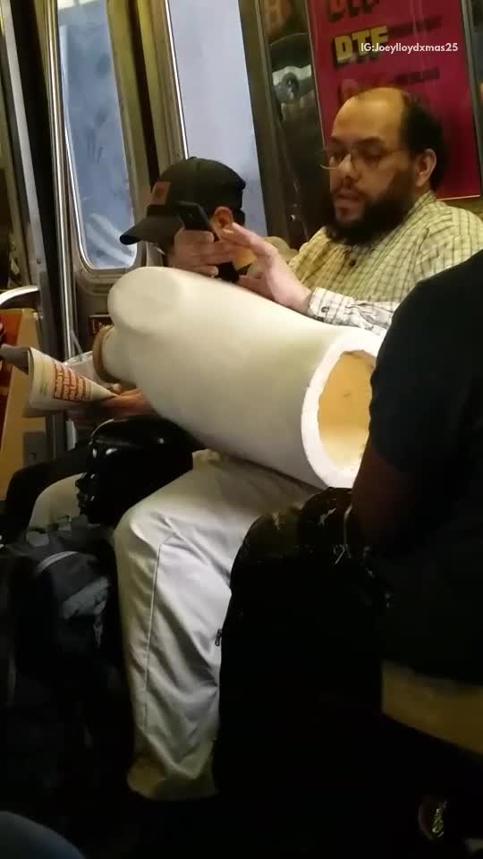 Black doll head between guys legs and backpack subway