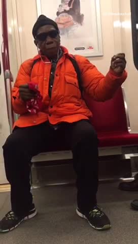 Woman in orange dances on subway seat