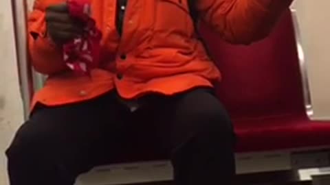 Woman in orange dances on subway seat