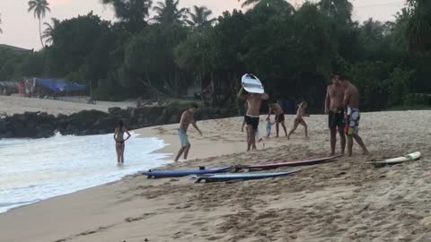 Guy poses picture of white surfboard on beach