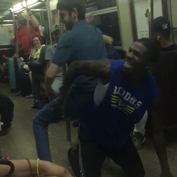 Man in blue cut off shirt dances under legs of another man