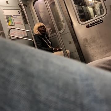 Man in blonde wig black hoodie talks to self on subway