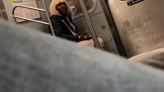 Man in blonde wig black hoodie talks to self on subway