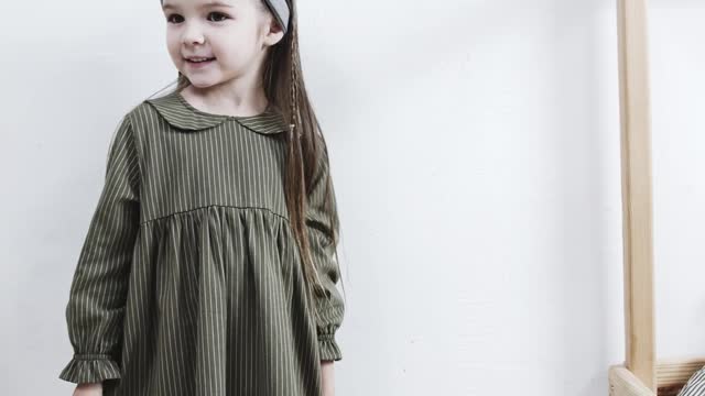 A Girl Standing In The Playroom, Happily Showing Her Dress