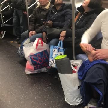Man gives foot rub to his wife on subway train