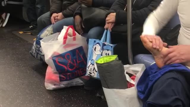 Man gives foot rub to his wife on subway train