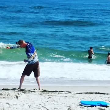 A man in a blue long sleeve shirt exercising on beach