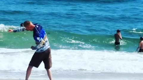 A man in a blue long sleeve shirt exercising on beach