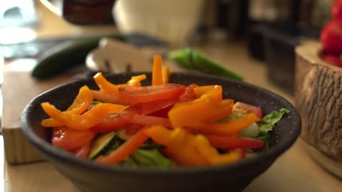 Close Up of Female Hands Adding Sliced Pepper to Salad Bowl