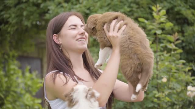 A young beautiful Caucasian woman plays with a cute puppy on her lap