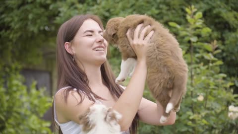 A young beautiful Caucasian woman plays with a cute puppy on her lap