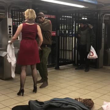 Woman and man dance together next to subway station turnstiles
