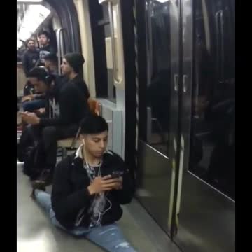 Man on phone texting does splits while on subway