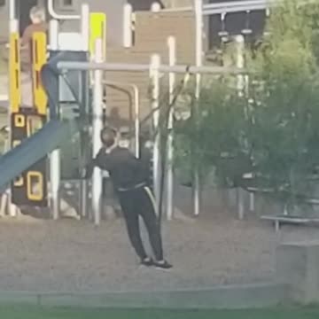 Man in black exercising in playground with ropes
