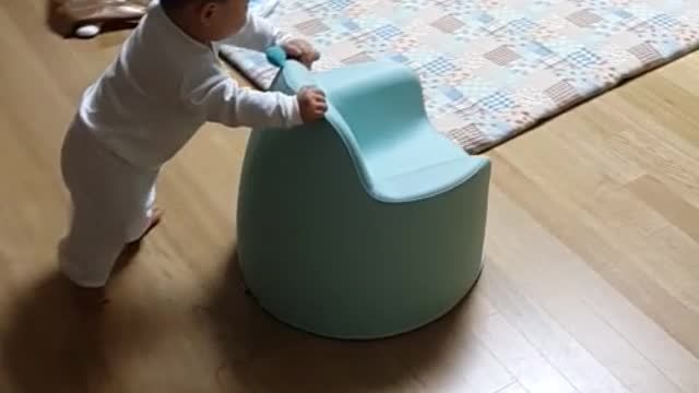 A baby practicing walking using a chair.