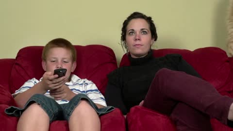 Family watching TV on couch with cat